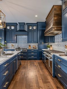 a large kitchen with blue cabinets and wood flooring, along with an island in the middle