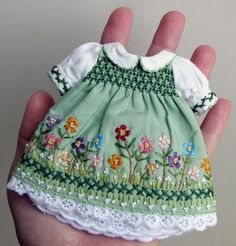 a hand holding a small green dress with flowers on it