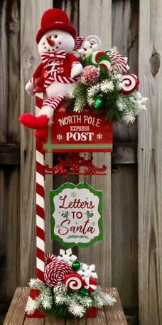 a christmas post with candy canes and snowmen on it, sitting in front of a wooden fence