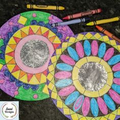 two colorful paper plates with crayons on them next to markers and pencils