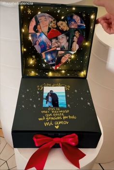 an open box that has pictures on it and a red ribbon around the lid is shown