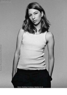 a black and white photo of a woman in a tank top with her hands on her hips