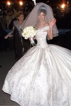 a woman in a wedding dress waving at the camera