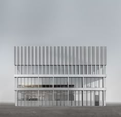 an architectural rendering of a white building with vertical lines on the front and sides, against a gray sky