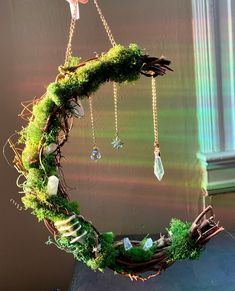 a wreath with moss and crystals hanging from it