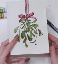 two hands holding a card with watercolors on it