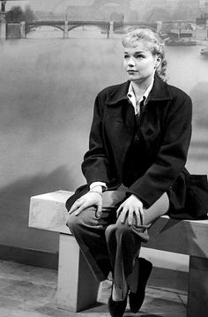 a black and white photo of a woman sitting on a bench