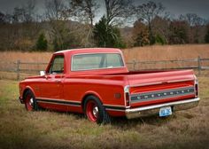 an old red pickup truck parked in a field