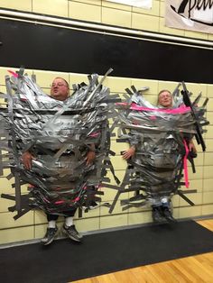 two people standing in front of a wall made out of duct tape