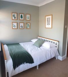 a white bed sitting in a bedroom next to two framed pictures