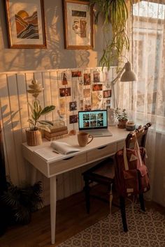 a laptop computer sitting on top of a white desk next to a plant and window