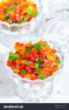 two glass bowls filled with gummy bears on top of a white tablecloth stock photo