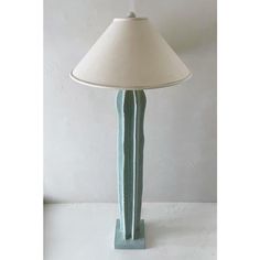 a table lamp with a white shade on it's base and a green column