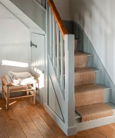 there is a wooden stair case next to the carpeted stairs in this house with white walls and wood flooring