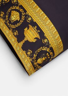 the black and gold scarf has an ornate design on it's side, along with a golden border