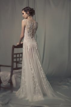 a woman in a wedding dress standing next to a chair