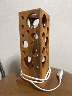 a wooden object sitting on top of a table next to a charger plugged in