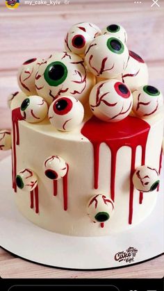 a white cake with red icing and green eyes painted on the top is sitting on a plate