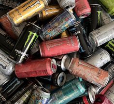 a pile of cans filled with different types of drinks and energy drinks in each one