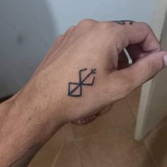 a person's hand with a small tattoo on the left side of their arm