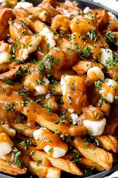 a bowl filled with french fries covered in gravy and topped with parsley