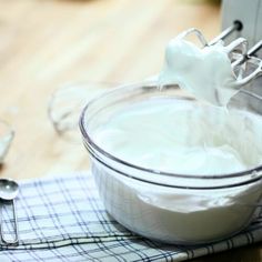 a hand mixer mixing white cream in a bowl