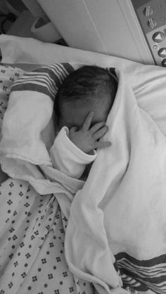 a black and white photo of a baby wrapped in a blanket