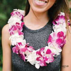 a woman wearing a flower lei with pink and white flowers on her neck, smiling at the camera