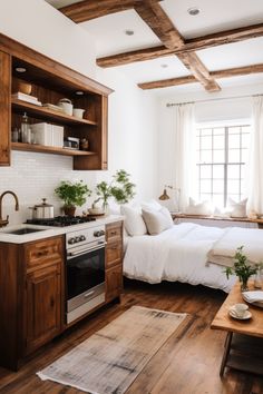 a kitchen with wood floors and white walls, an oven, sink, and bed in it