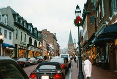 cars are parked on the street in front of shops and buildings with christmas wreaths