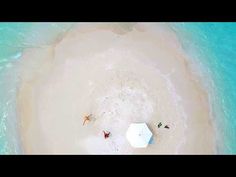 an aerial view of people on the beach with umbrellas in the sand and clear blue water