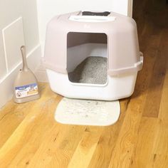 a cat is sitting in a litter box on the floor next to a mop