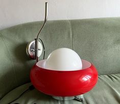 a red and white lamp sitting on top of a green couch