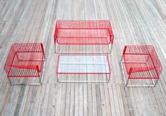 three red chairs and two tables sitting on a wooden floor in front of each other