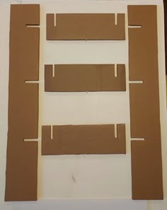 cardboard cutouts are arranged on top of a piece of paper with tape sticking out of them