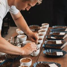 a man is preparing cups of coffee on a table