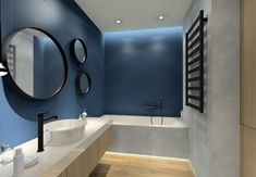 a modern bathroom with blue walls and white counter tops, along with an oval mirror on the wall