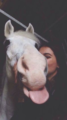 a woman is hugging a horse with her tongue out and it's head sticking out