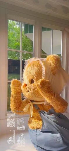 a teddy bear sitting on top of a window sill