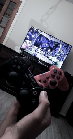 a person holding a video game controller in front of a tv with the television on