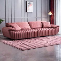 a living room with a pink couch and rug on the floor next to a potted plant