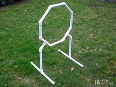 a white toilet sitting on top of a lush green field next to a garden hose holder