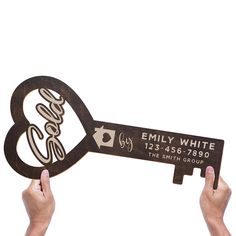 two hands holding up a wooden key shaped like an eiffel with the words family white on it