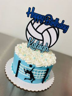 a birthday cake with a volleyball theme and happy birthday sign in the top layer, sitting on a table