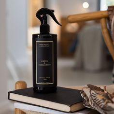 a bottle of black liquid sitting on top of a table next to an open book