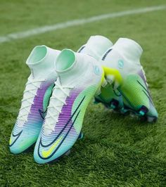 two soccer cleats sitting on top of a green field