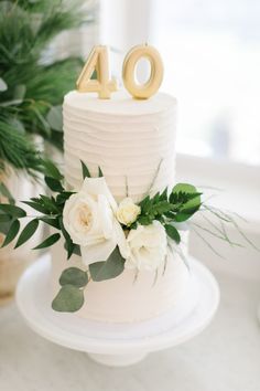 a white cake with flowers and greenery on top