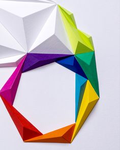 an origami geometrical design made up of different colors and shapes on white paper