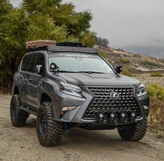 the front end of a gray suv parked on a dirt road