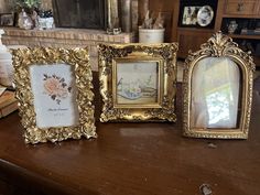 three gold framed pictures sitting on top of a wooden table next to a fire place